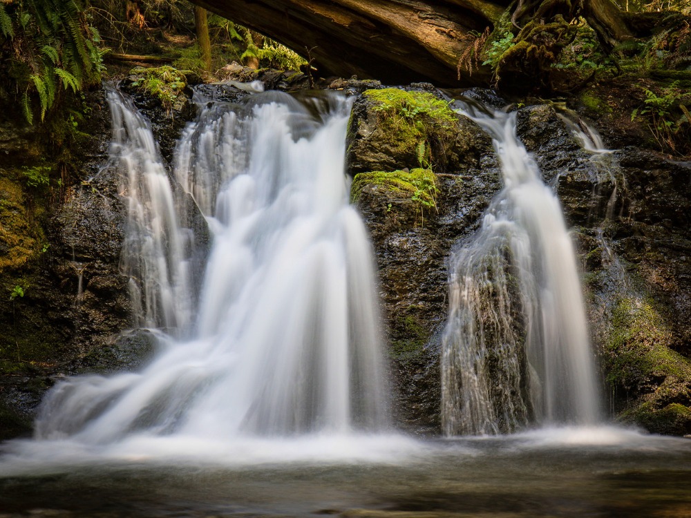 two waterfalls flowing into dark river