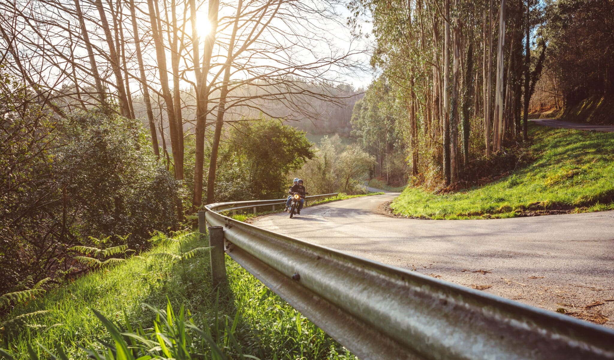 Senior couple riding motorbike along forest road