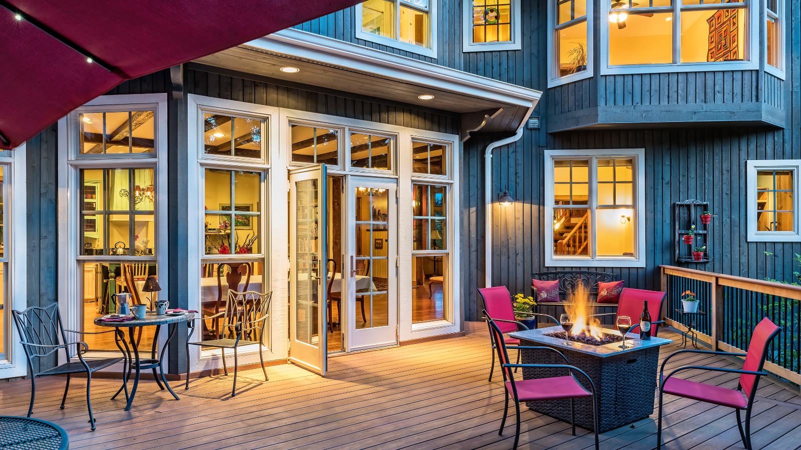 Exterior view of property's wooden deck with wicker fire pit, pink and black patio chairs, and another wrought iron small round table and chairs