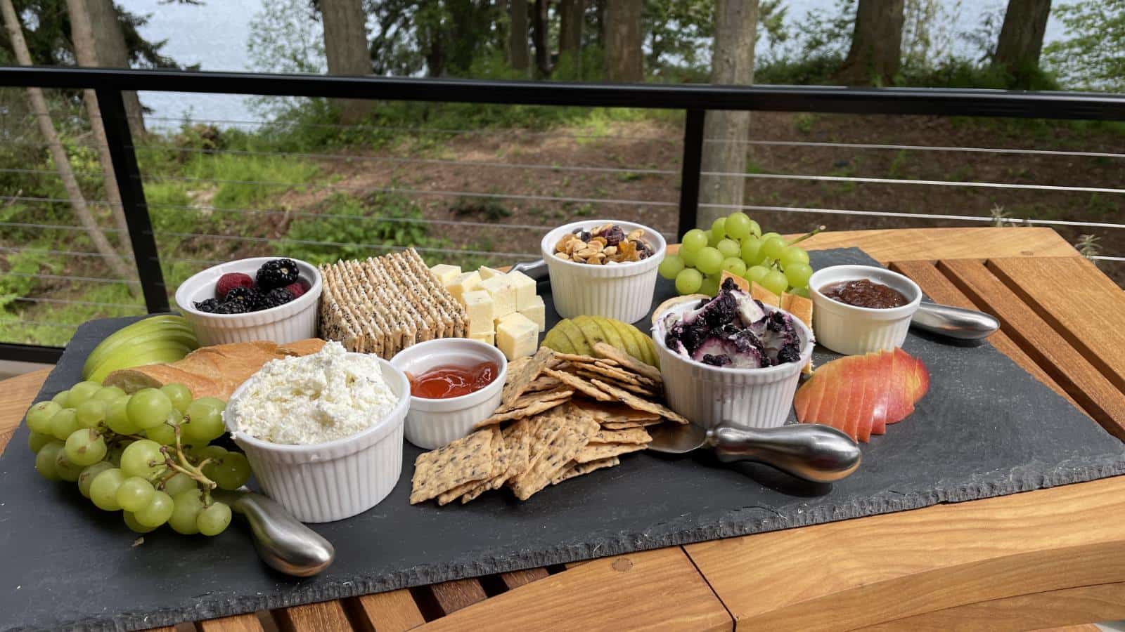 Close up view of gray slate charcuterie board filled with fruit, cheese, crackers, and nuts