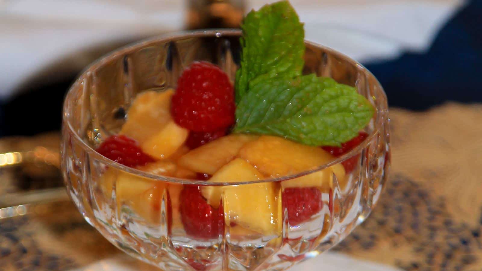 Close up view of fruit in glass dish with sprig of mint