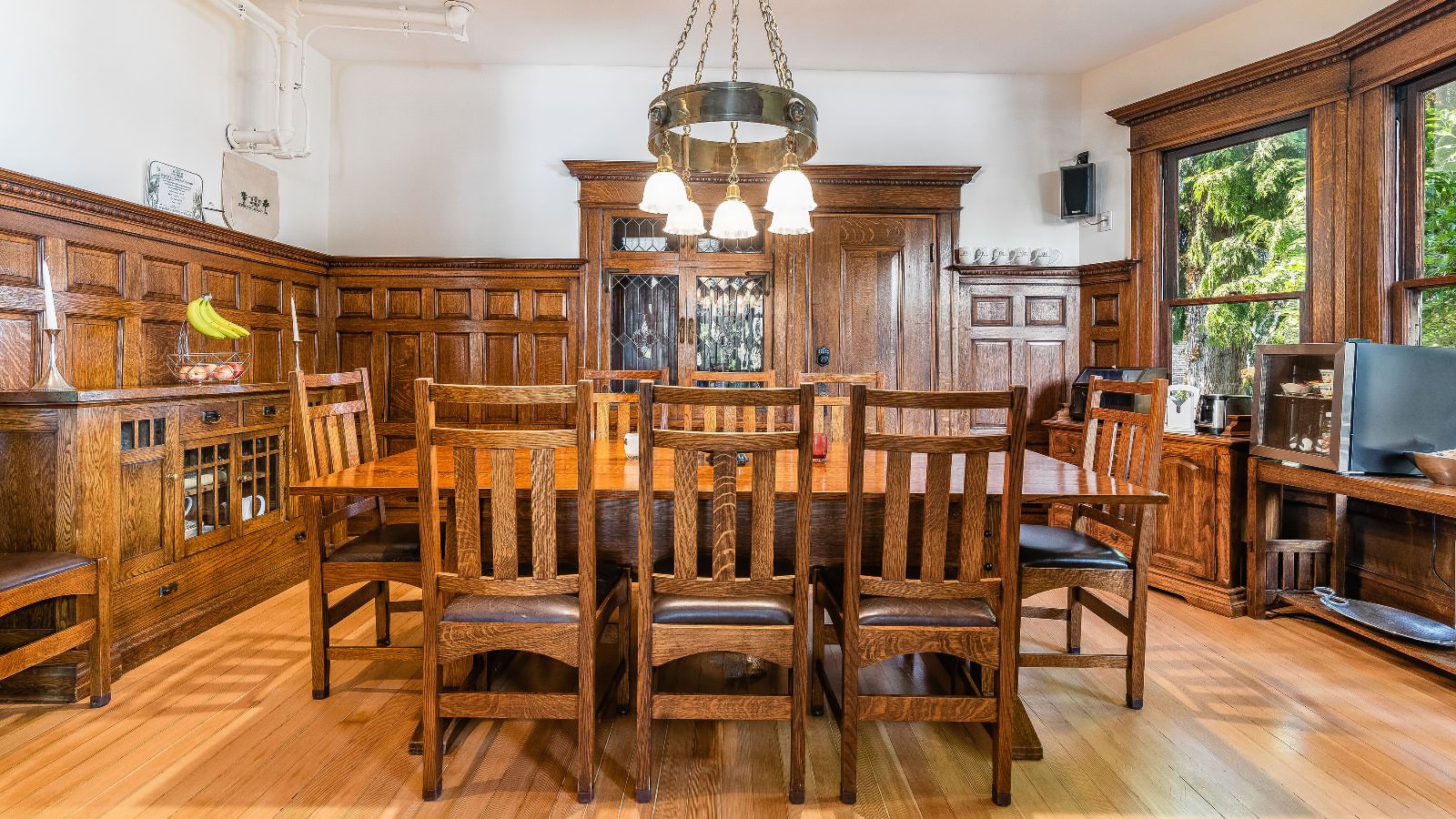 Dining room with white walls, wooden paneling, wooden trim, wooden table, wooden chairs, and large windows