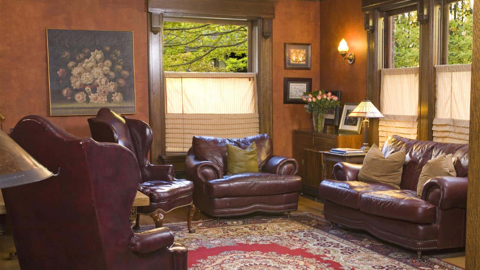 Great room with light brown walls, hardwood flooring, leather chairs and loveseats, and large windows