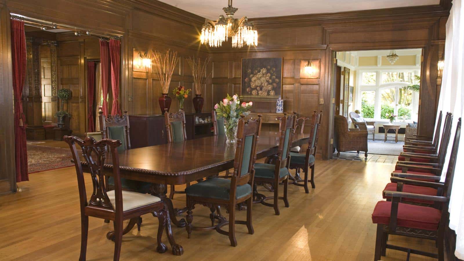 Large dining room with wooden paneling, hardwood flooring, and large wooden table with chairs