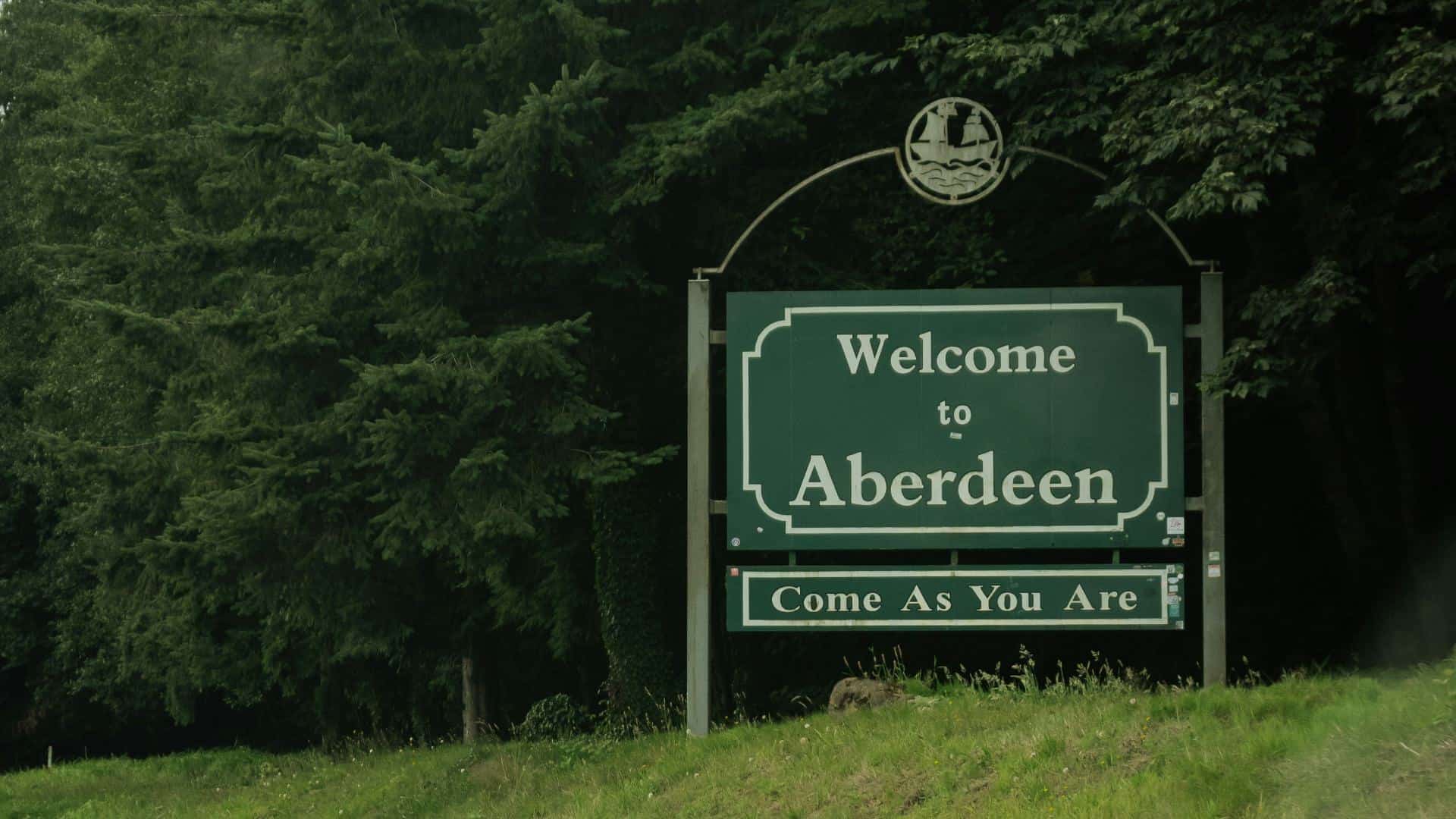 Green Welcome to Aberdeen sign surrounded by large green trees