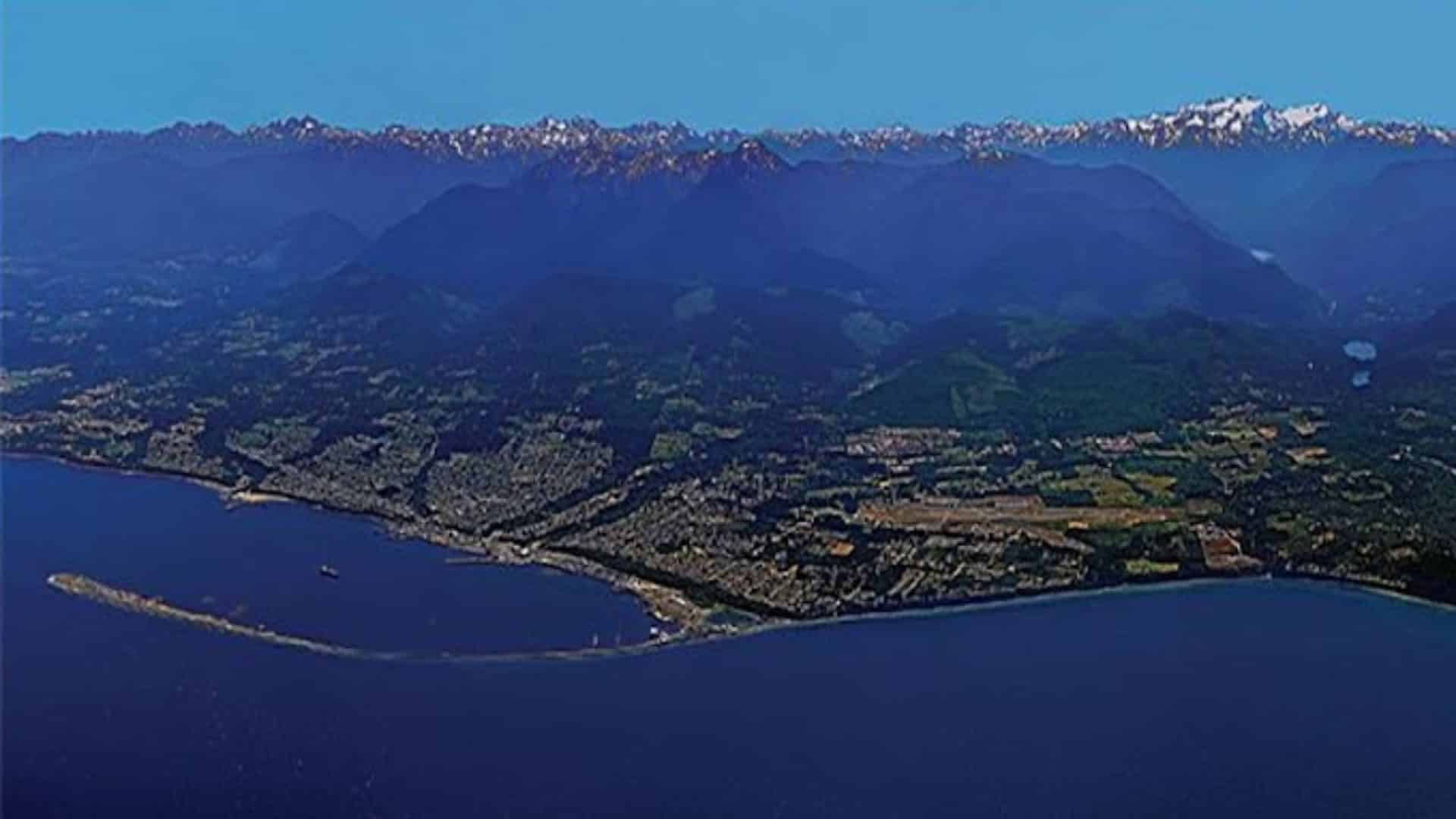 Aerial view of a town on the water with mountain range in the background