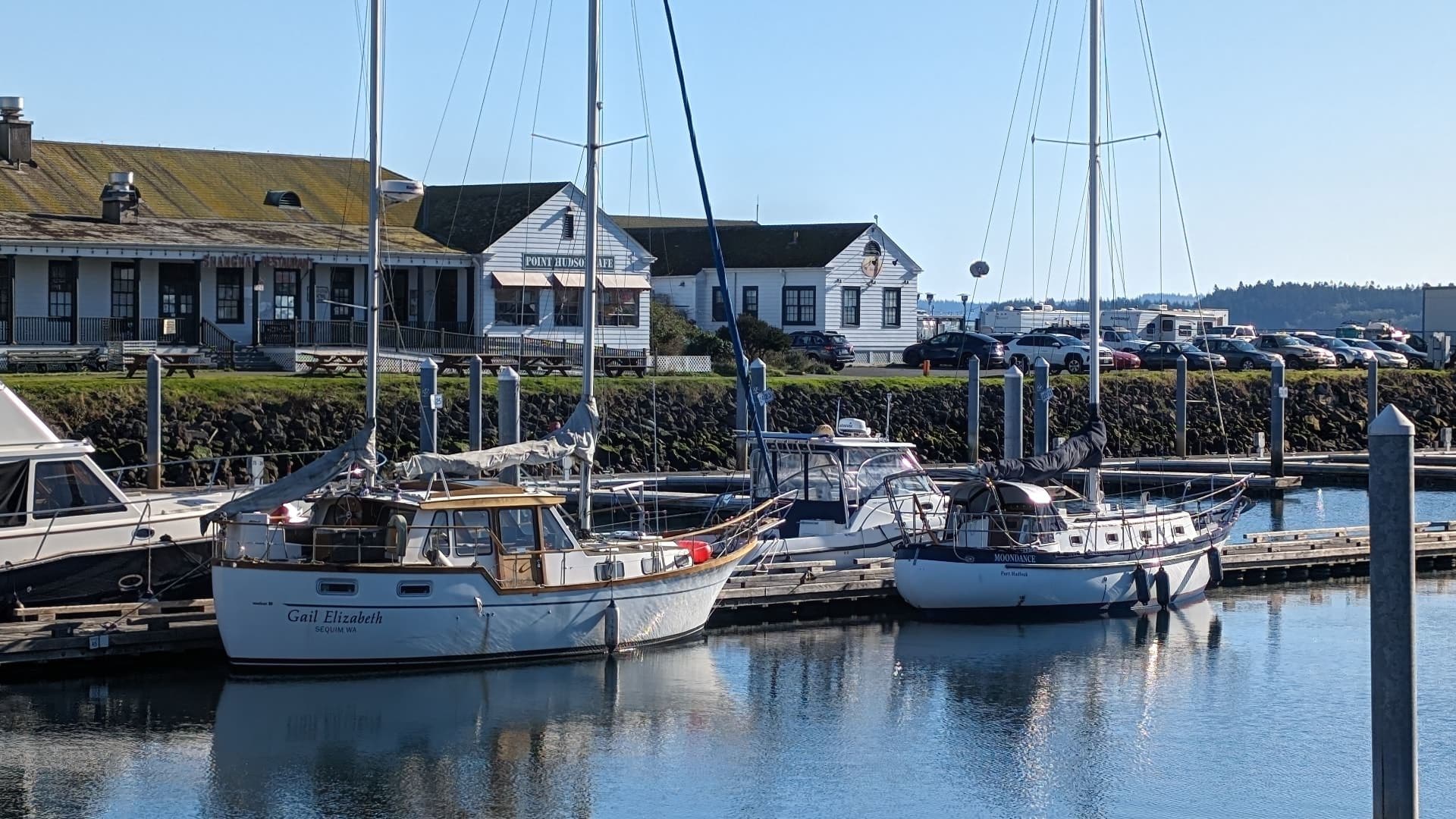 Multiple sailboats docked at a marina on calm water