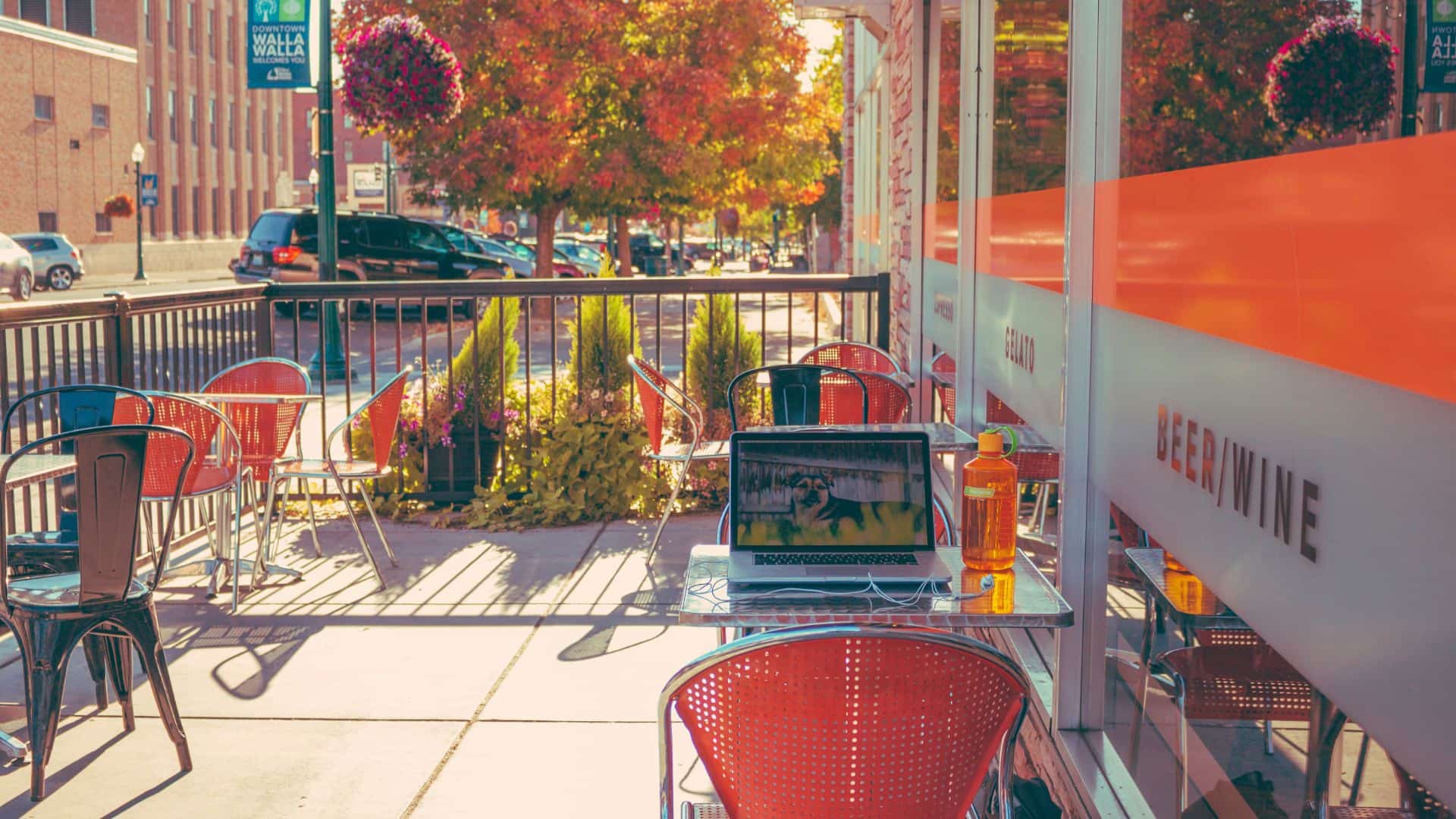 Restaurant's fenced in concrete patio with metal tables and chairs in a downtown area