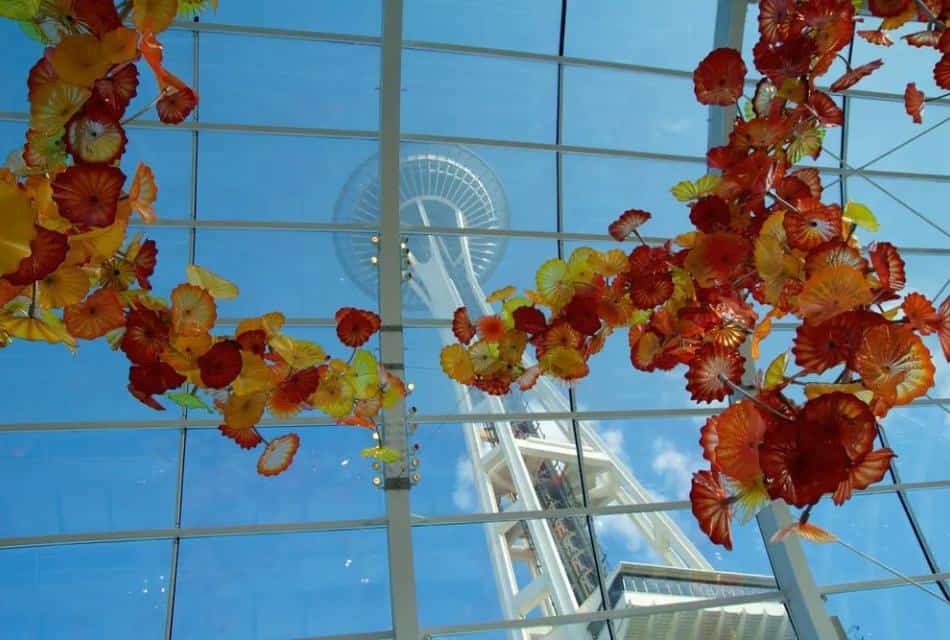 View of Seattle Space Needle from the ground through glass ceiling with red, orange, and yellow glass flowers