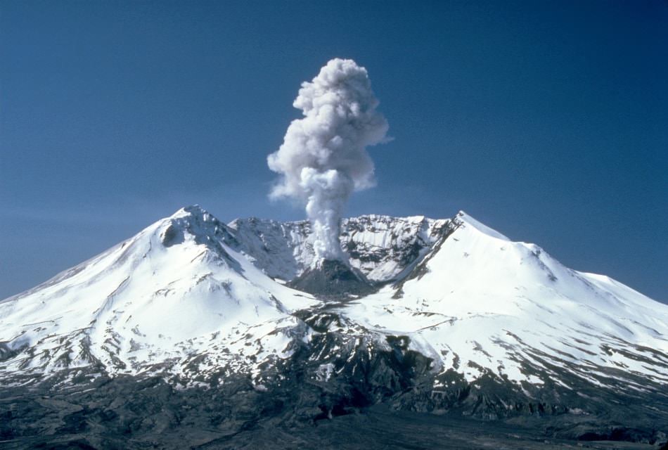 Volcano covered with snow with small eruption of smoke coming out the middle