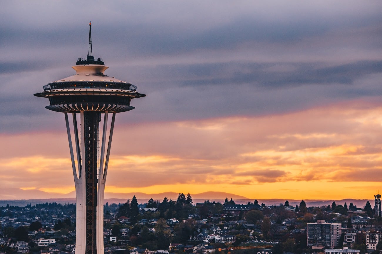 Seattle space needle in foreground with orange purple sunset in background